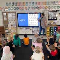 Interpreter teachers alphabet signs to a group of students